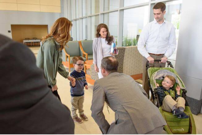 Daniel Mark Cotton is smiling in a baby carrier on the left side during a visit to UAMS.